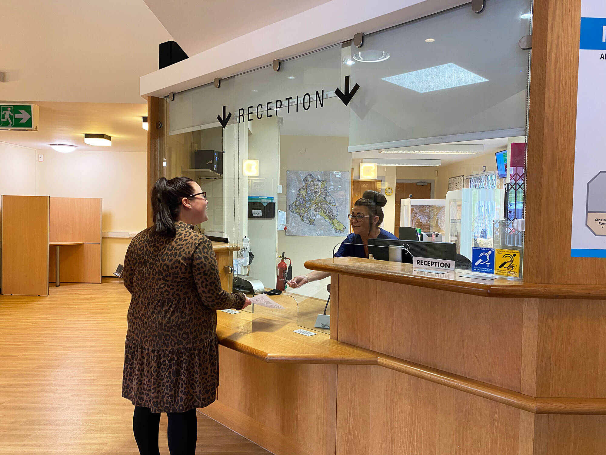 Moorcroft Medical Centre reception area with a receptionist taking a paper from a patient