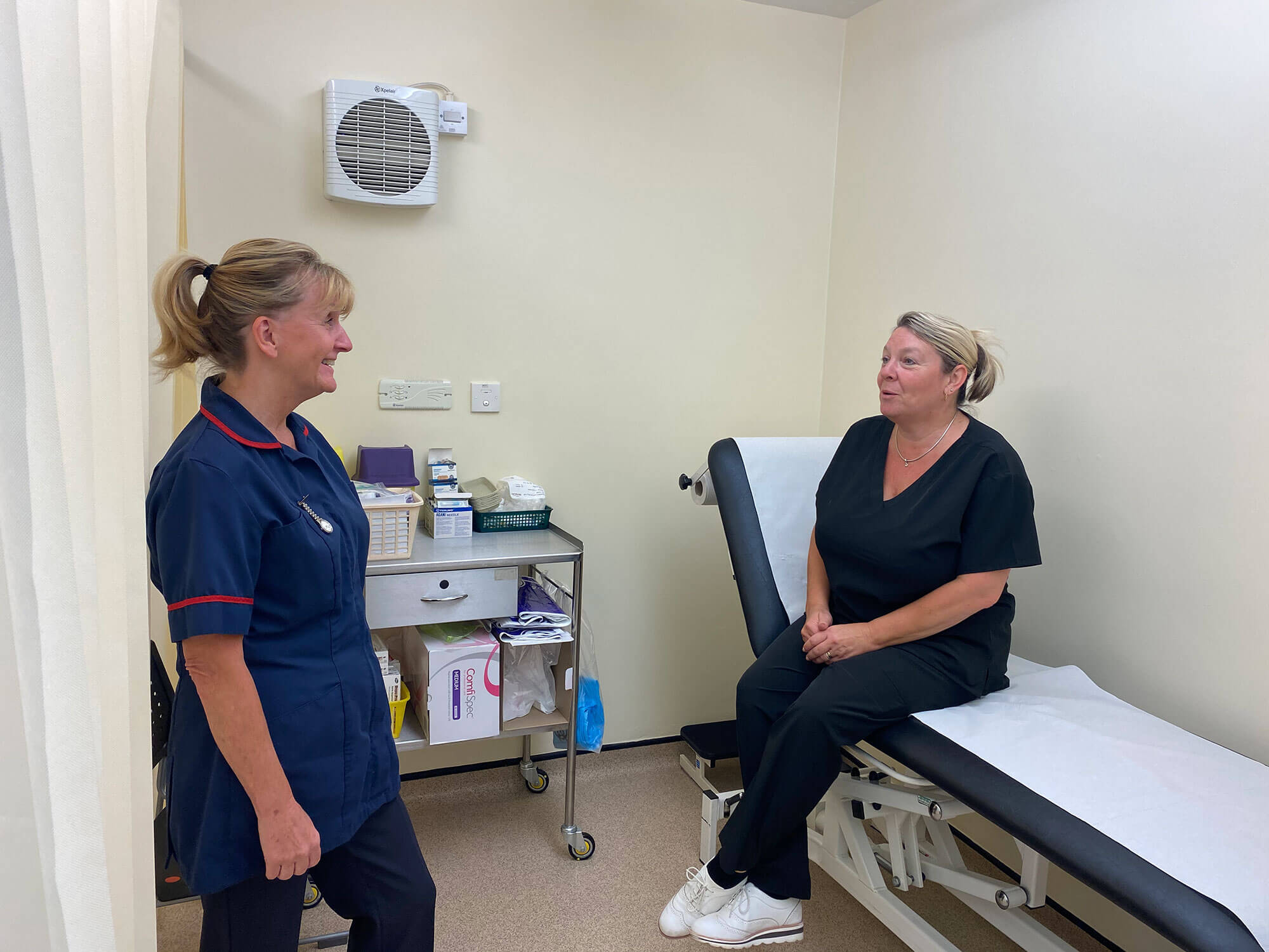 A nurse consulting with a patient who is sat on a gurney